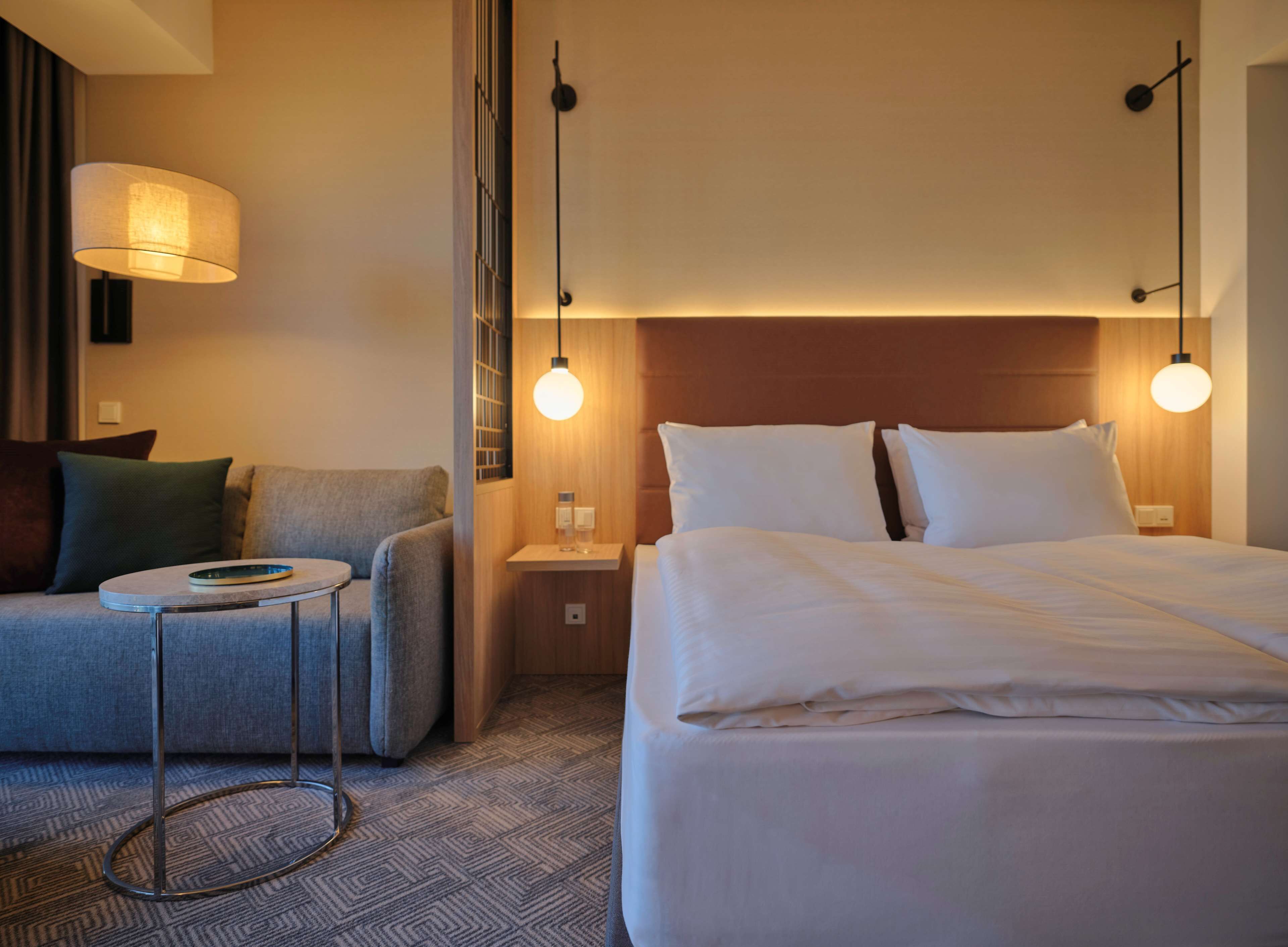 Une chambre d’hôtel avec un lit, un canapé, une petite table et deux lampes de chevet.