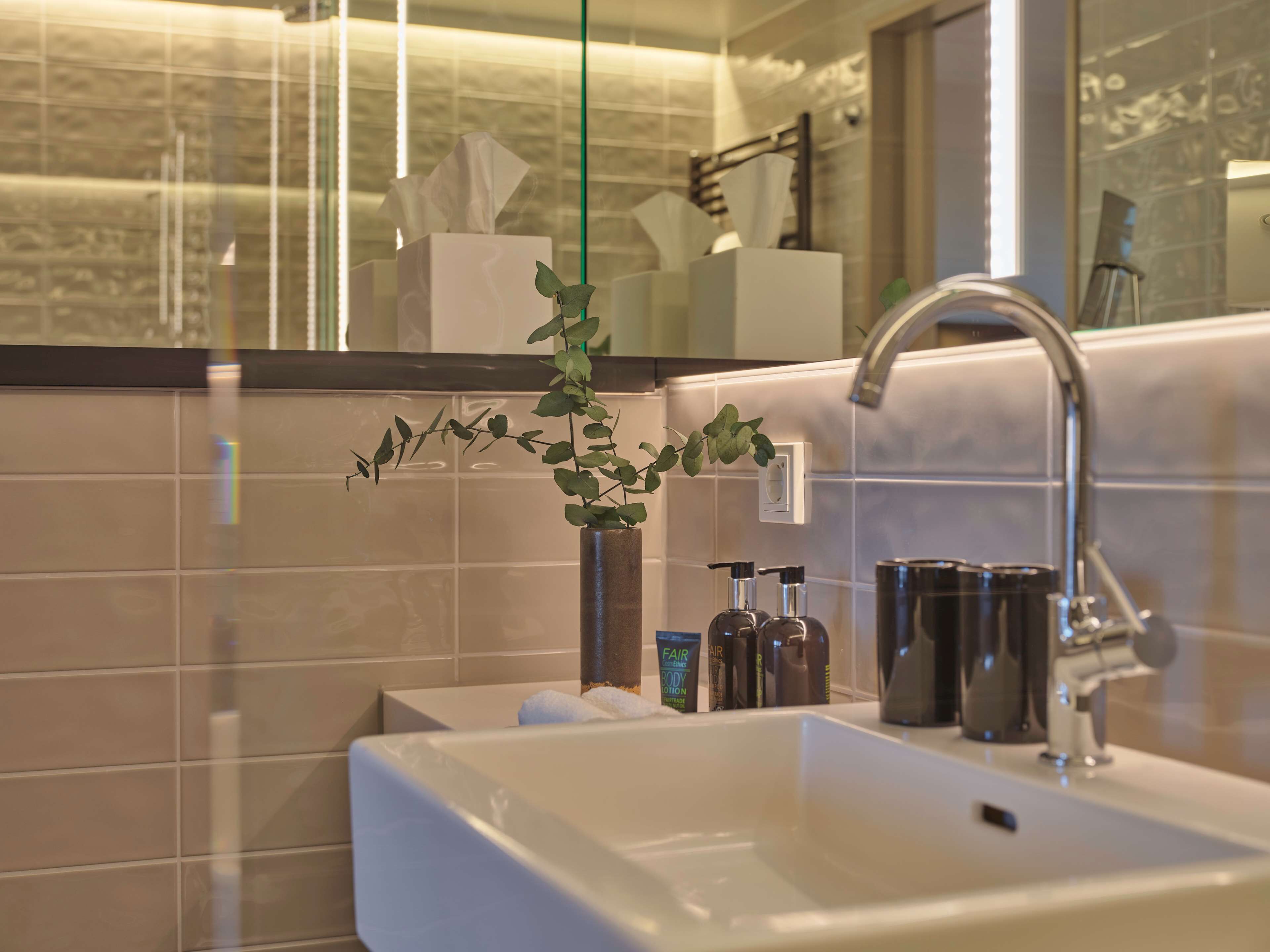 A modern bathroom with a white sink, a mirror, and toiletries.
