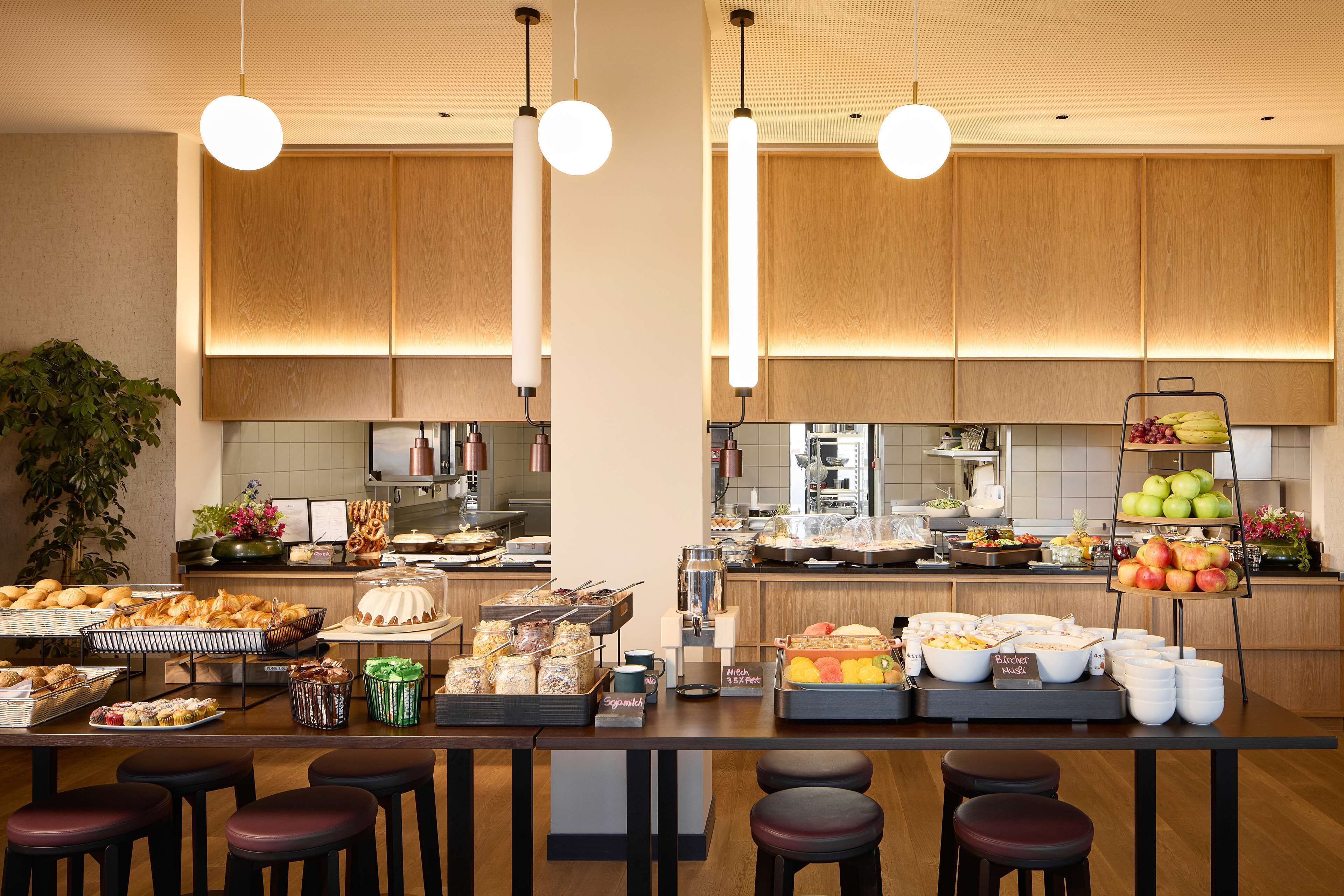 Una cocina moderna con armarios de madera, una barra desayunadora con taburetes y diversos alimentos a la vista.