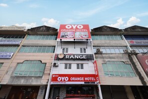 Un hotel con un llamativo letrero OYO Orange Hotel, un letrero Range y un letrero de Luna Material Handling.