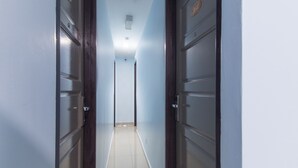 A narrow hallway with doors on both sides, leading to a bright room at the end. - OYO 90296 Red Orange Hotel Port Klang (Pelabuhan Klang)