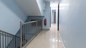 A corridor with a metal railing, a fire extinguisher, and a door at the end. - OYO 90296 Red Orange Hotel Port Klang (Pelabuhan Klang)