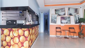 A reception area with a counter, chairs, and a wall with pictures. - OYO 90296 Red Orange Hotel Port Klang (Pelabuhan Klang)