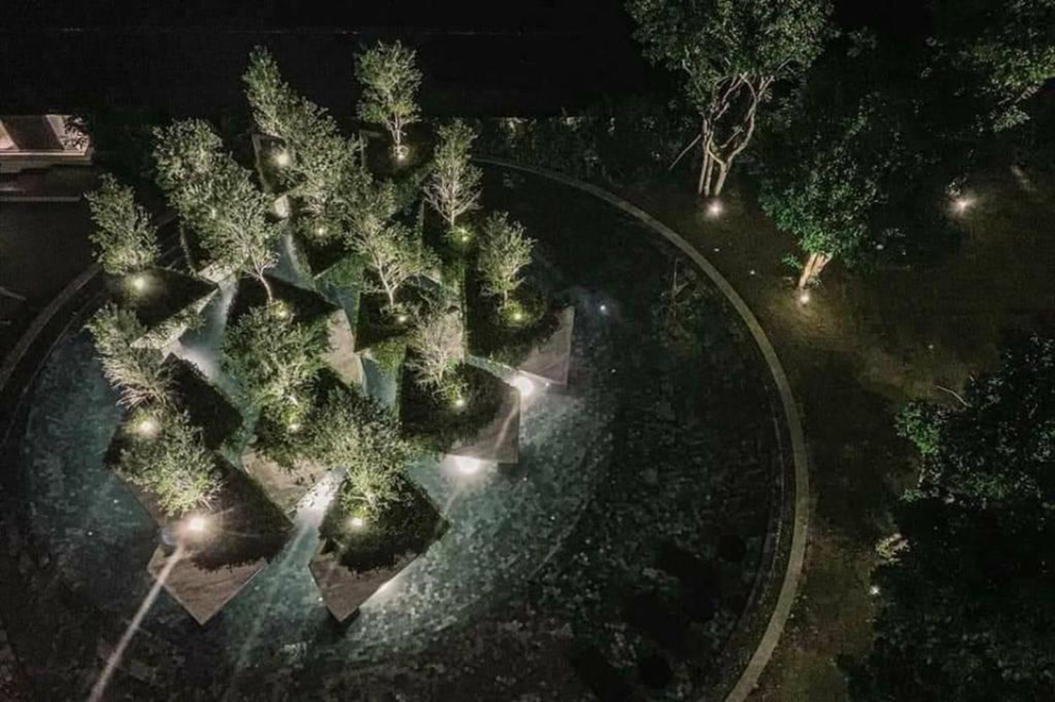 A nighttime aerial view of a landscaped area with trees and pathways.