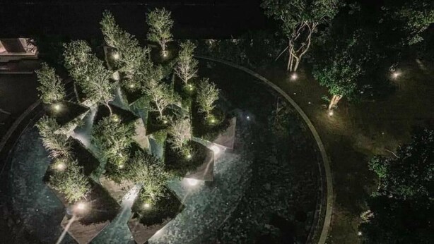 A nighttime aerial view of a landscaped area with trees and pathways.