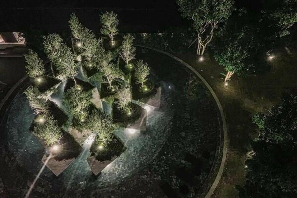 A nighttime aerial view of a landscaped area with trees and pathways.