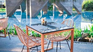 A table and chairs by a pool with a concrete structure in the background. - Livist Resort Phetchabun (Phetchabun)