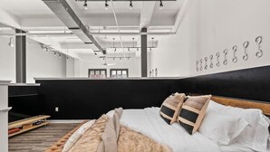 Una habitación de hotel moderna con una cama grande, un banco de madera y una decoración en blanco y negro.