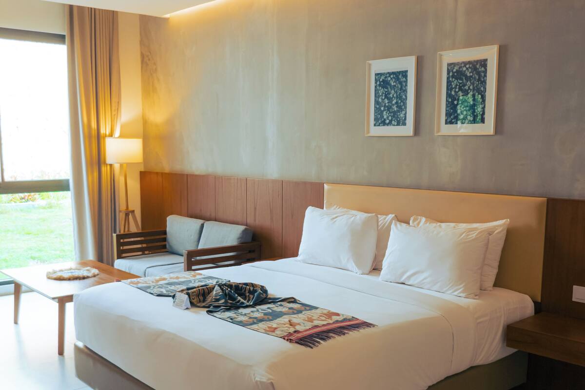 Ein Hotelzimmer mit einem großen Bett, einem kleinen Tisch, einem Stuhl und zwei gerahmten Bildern an der Wand.