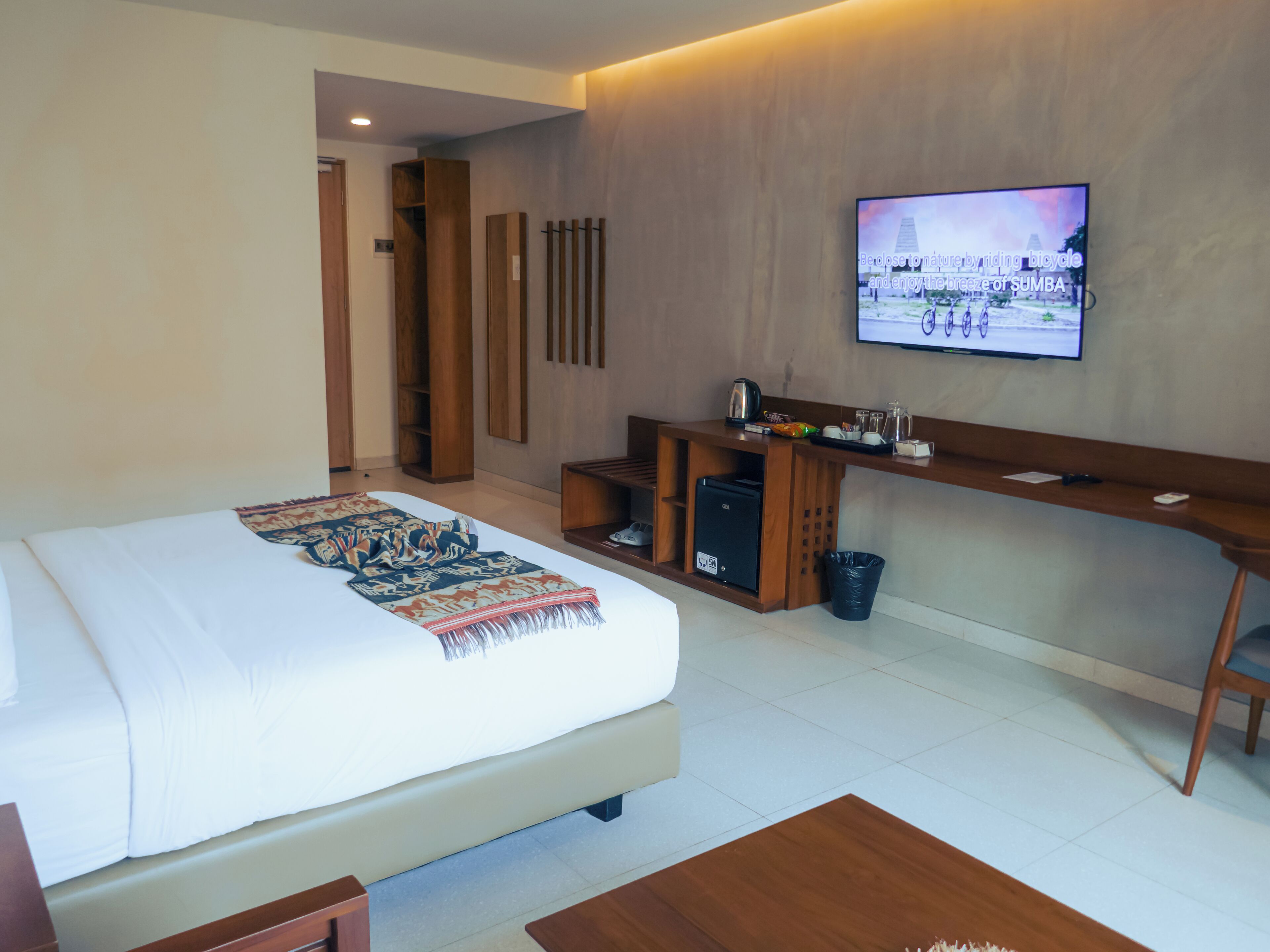 A hotel room with a bed, a desk, a television, and a coffee machine.