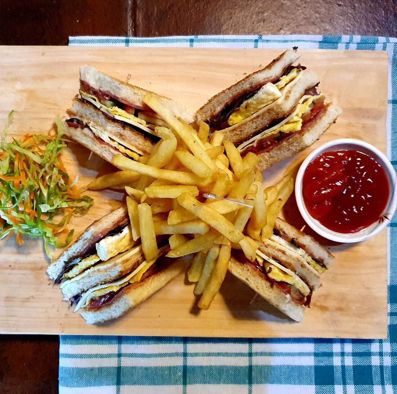 Un sándwich con papas fritas y kétchup sobre una tabla de madera.