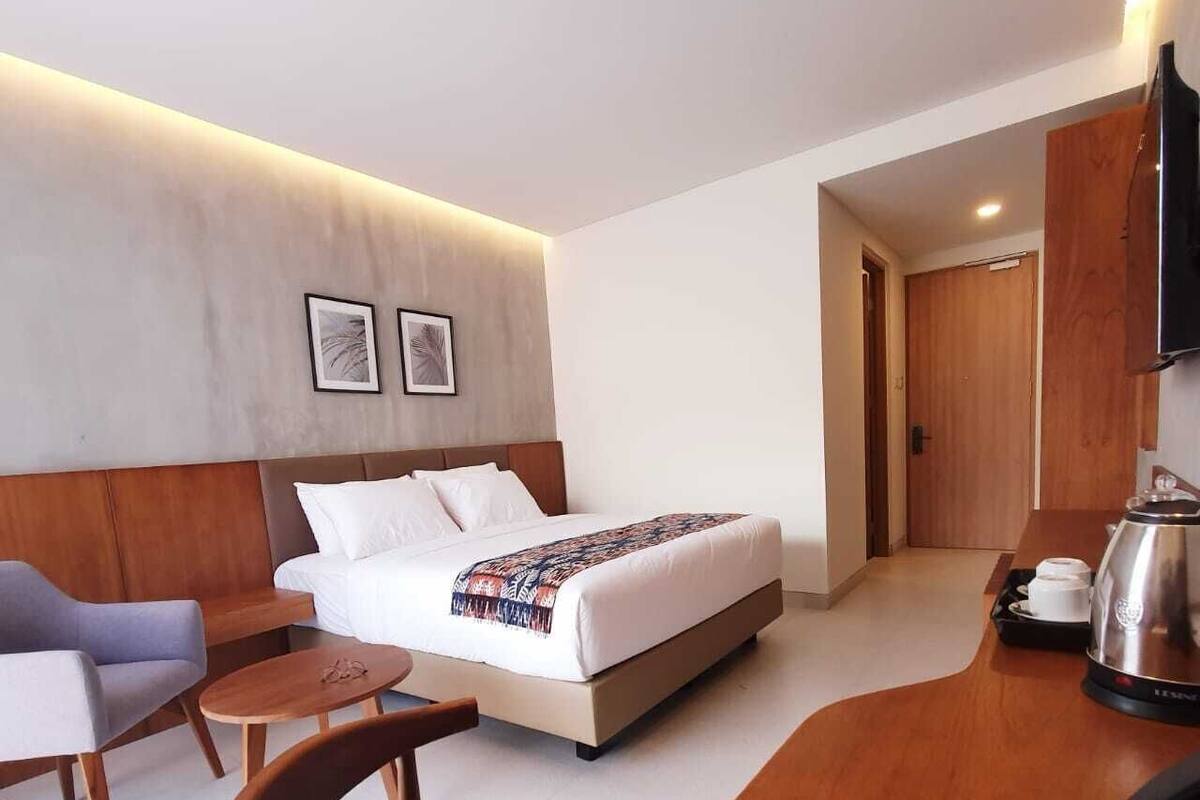 Ein Hotelzimmer mit Bett, Schreibtisch, Stuhl, Kaffeemaschine und Fernseher.