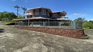 A large, two-story house with a stone foundation and metal fence. - Hotel O Rb Homestay & Farms (Kuching)