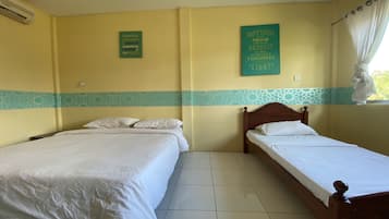 A room with two single beds, a window with curtains, and motivational wall art.
