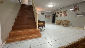 A staircase leading to a landing with a tiled floor, a bench, and two wicker chairs. - Hotel O Rb Homestay & Farms (Kuching)