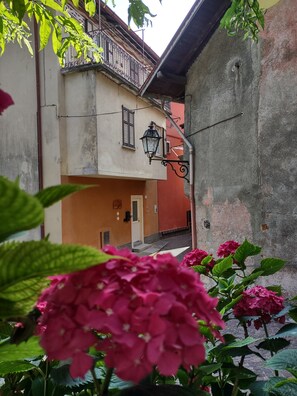 A narrow alleyway with a building featuring a balcony, a door, and a lamp post.