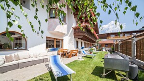 Une terrasse avec un long banc, un barbecue et une petite table.