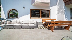 Une terrasse avec un canapé, une table et un banc en bois.