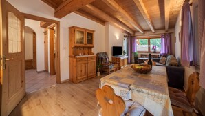 A wooden interior with a dining table, chairs, a cabinet, and a television. - Apartment ‘Sonnenparadies 4’ with Mountain View, Wi-Fi & Garden (St. Martin in Passeier / Quellenhof)