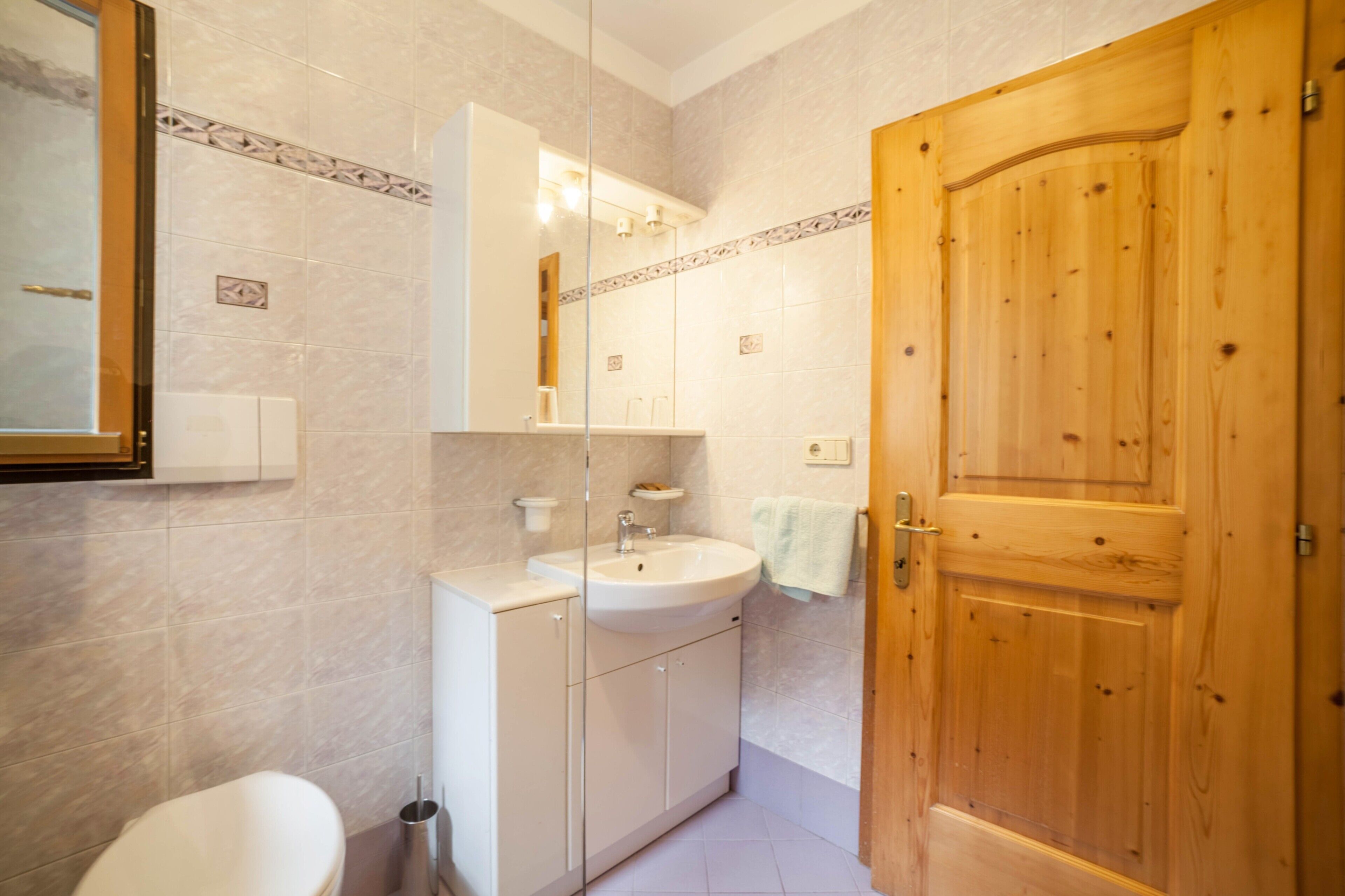 A bathroom with a white sink, mirror, and wooden door.