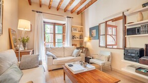 A cozy living room with a sofa, a coffee table, a side table, and a bookshelf. - Spacious townhouse in the heart of Sóller. (Soller)
