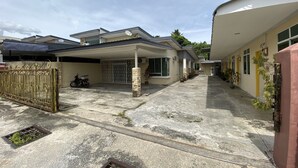 A residential area with houses, a gated entrance, and a motorcycle parked near the gate. - Hotel O Taman Kota Homestay (Keningau)