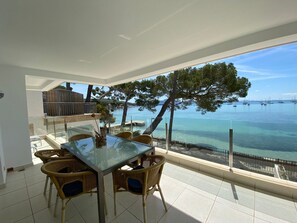 A balcony with a glass table and wicker chairs, overlooking a clear sea and boats. - Holiday Home Catalina 2A Tres Dormitorios with Sea View, Wi-Fi & Terrace (Puerto Pollensa)