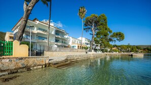 Un hotel frente al mar con aguas cristalinas, un muro de piedra y una puerta verde.