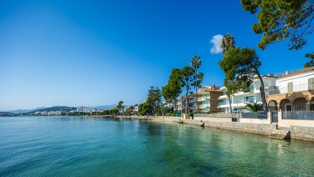 Un hotel frente al mar, con vista despejada, un camino de piedra y edificios con balcones.