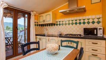 Una cocina con mesa, sillas, microondas y vistas a través del ventanal.