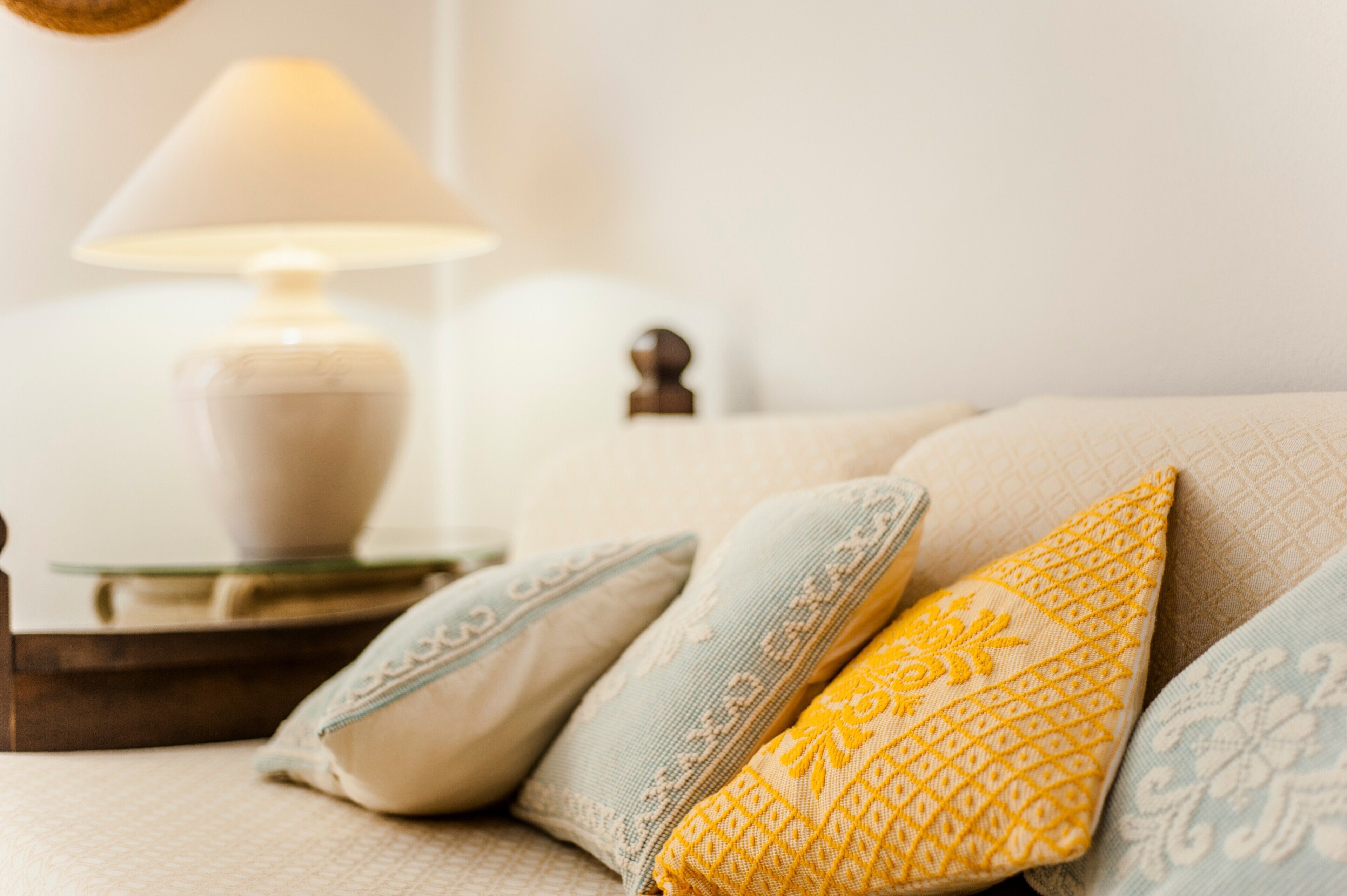 A bed with pillows and a bedside table with a lamp.