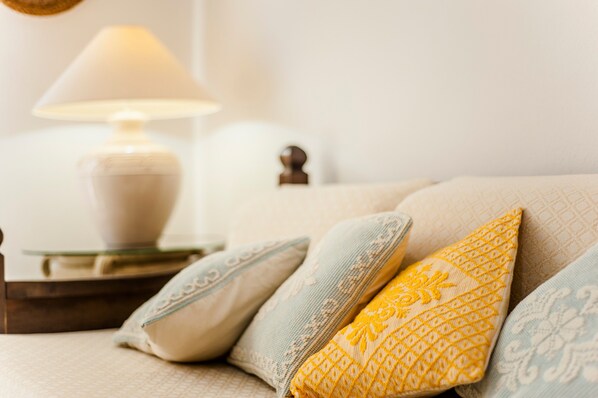 A bed with pillows and a bedside table with a lamp.