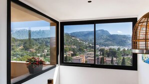 Une pièce dotée d’une grande fenêtre donnant sur une ville et des montagnes.