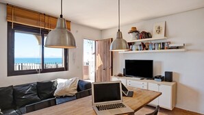 Et moderne opholdsrum med et træspisebord, en bærbar computer, en sofa, et fjernsyn og en reol.