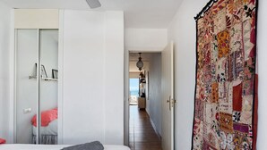 Et hotelværelse med en seng, et klædeskab, et dække og en gang, der fører til en balkon.