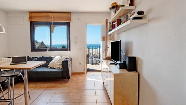 A modern living space with a sofa, a dining table, a TV, and a balcony with a view. - Apartment "Ático Heaven on Earth in Zahara" with Mountain and Sea Views (Zahara de los Atunes)