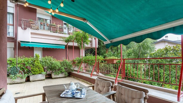 An outdoor patio with a wooden table, chairs, and a teapot set. - Beautiful two-bedroom energy efficient apartment with large equipped terrace (Brunate)