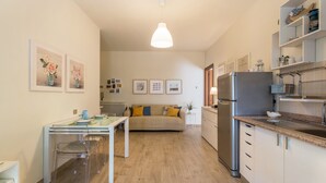A modern kitchen with a dining area, a sofa, and a refrigerator. - Beautiful two-bedroom energy efficient apartment with large equipped terrace (Brunate)
