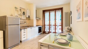 A compact kitchen with a refrigerator, oven, and dining table set for two. - Beautiful two-bedroom energy efficient apartment with large equipped terrace (Brunate)