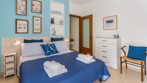 A bedroom with a bed, bedside tables, a dresser, a chair, and wall art. - Beautiful two-bedroom energy efficient apartment with large equipped terrace (Brunate)