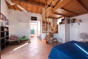 A room with a bed, a green bench, a chair, a fan, and a bookshelf. - Pet-friendly Vacation Home Villetta Rosa with Garden, Terrace, Balcony, BBQ & Wi-Fi (Lavagna)