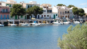 A marina with boats docked, buildings with balconies, and trees. - Villa Can Sard with Pool, Wi-Fi, Garden & Terrace (Portocolom)