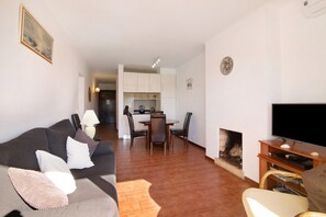 A living room with a sofa, TV, fireplace, and a dining area with chairs and a table.