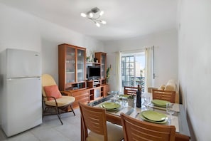 A dining area with a table set for four, a television, and wooden cabinets.