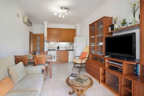 A living room with a sofa, coffee table, TV, and wooden cabinets.