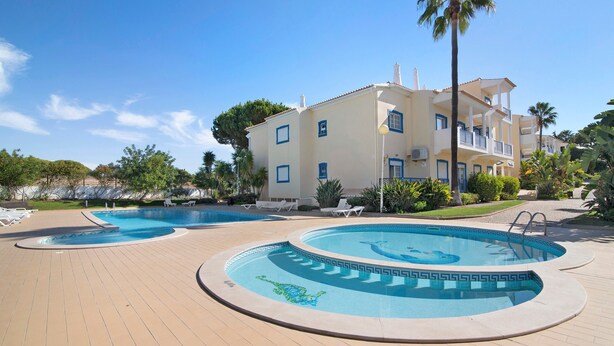 Ein Resort mit zwei Schwimmbecken, einem überdachten Bereich und einem Gebäude mit Balkonen.