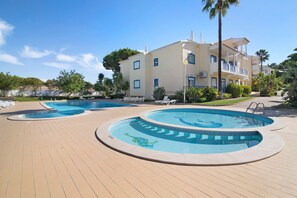 Un complexe hôtelier doté de deux piscines, d’un espace couvert et d’un bâtiment avec des balcons.