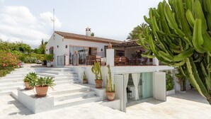 A white house with a tiled roof, a patio with steps, and potted plants. - Finca "Almijan Alegria" with Sea & Mountain Views, Pool, and Wi-Fi (Estepona)