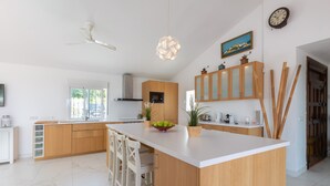 A modern kitchen with a central island, wooden cabinets, and a ceiling fan. - Finca "Almijan Alegria" with Sea & Mountain Views, Pool, and Wi-Fi (Estepona)