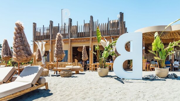 A beachside hotel with outdoor seating, large umbrellas, and a prominent 'B' sign. - Finca "Almijan Alegria" with Sea & Mountain Views, Pool, and Wi-Fi (Estepona)